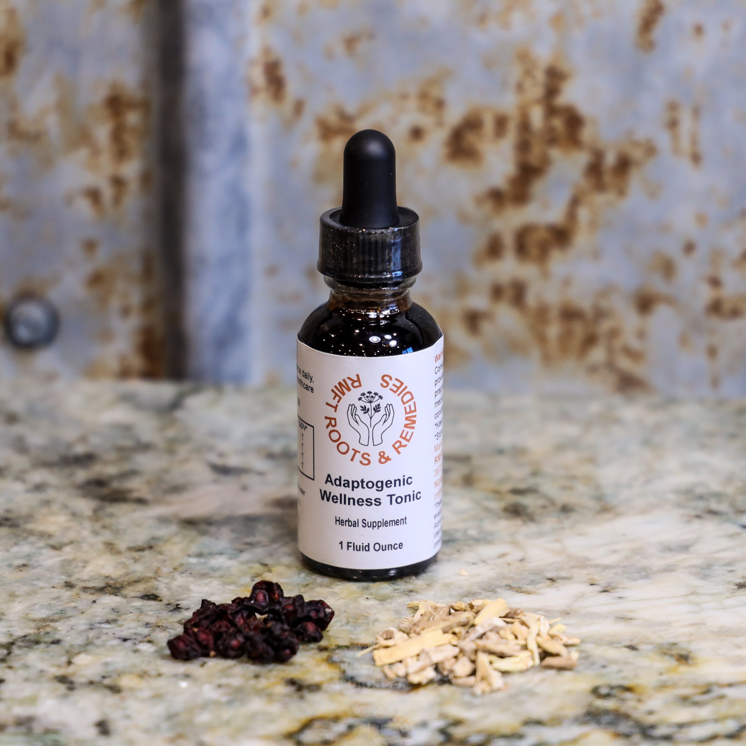 Bottle of Adaptogenic Wellness Tonic on a marble surface with dried herbs.