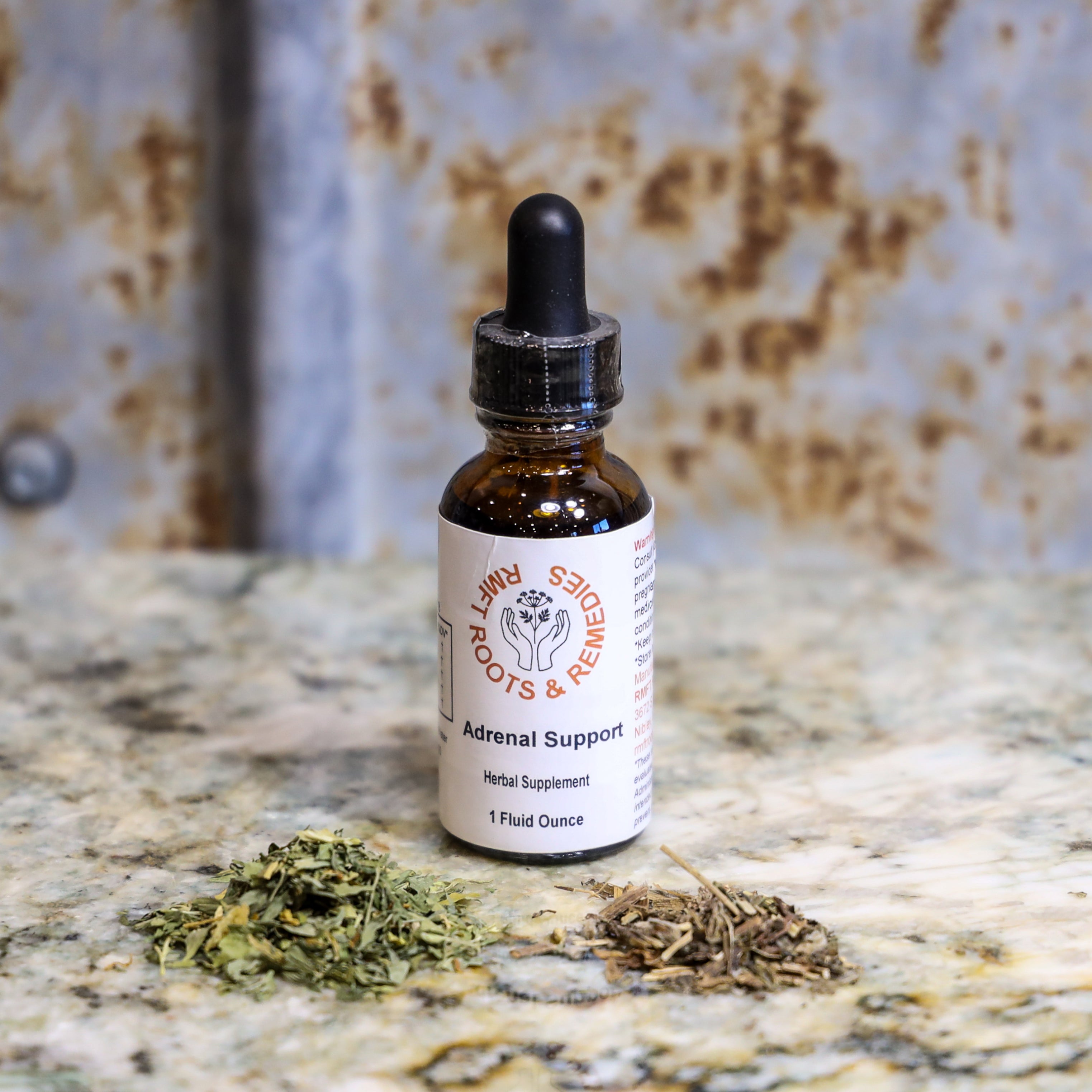 Bottle of 'Adrenal Support' herbal supplement with dried herbs on a textured surface
