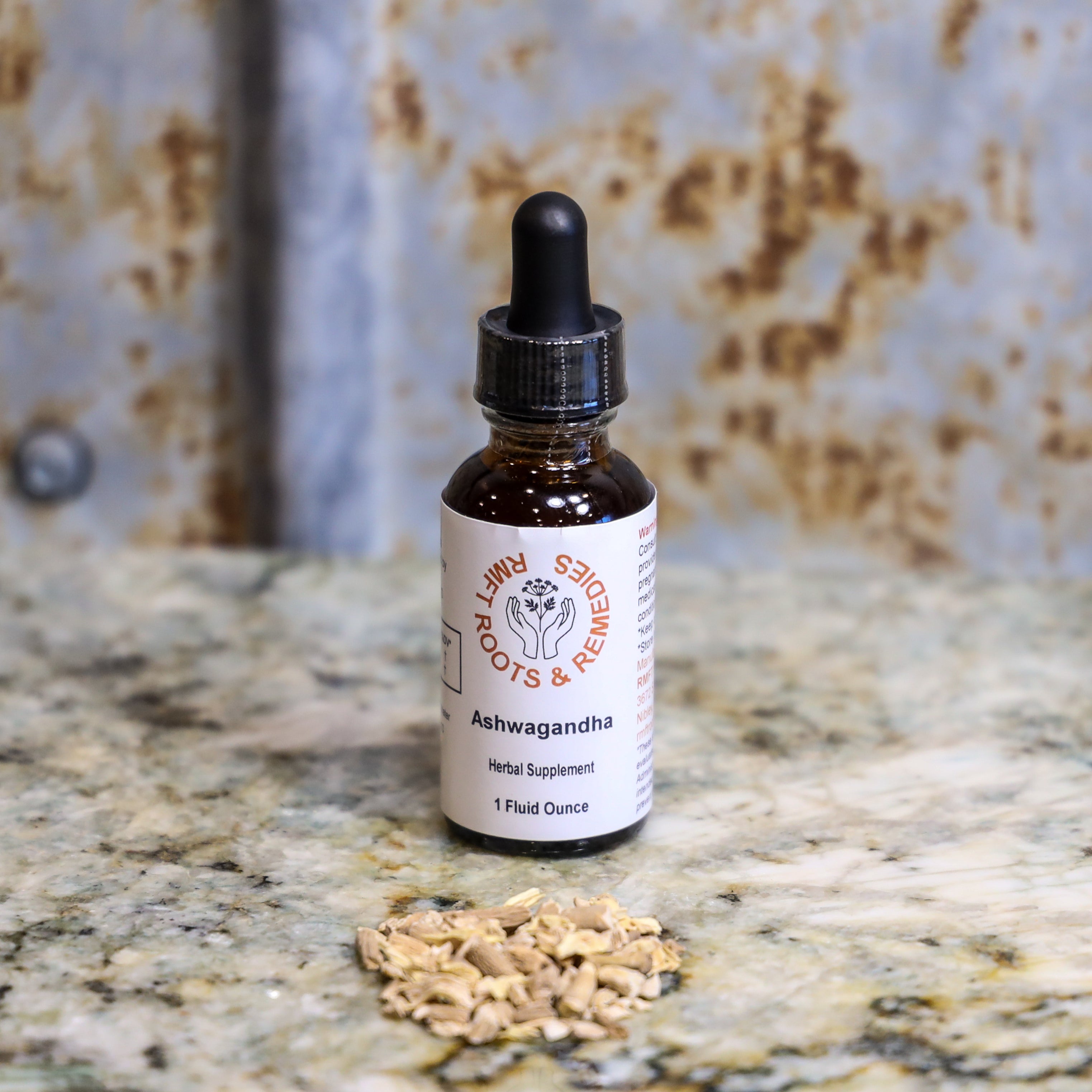 Bottle of Ashwagandha supplement with dried roots on a textured surface