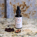 Bottle of 'Endocrine Support' supplement on a marble surface with dried herbs and powder.