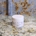 Jar of Lomatium Salve on a marble countertop.