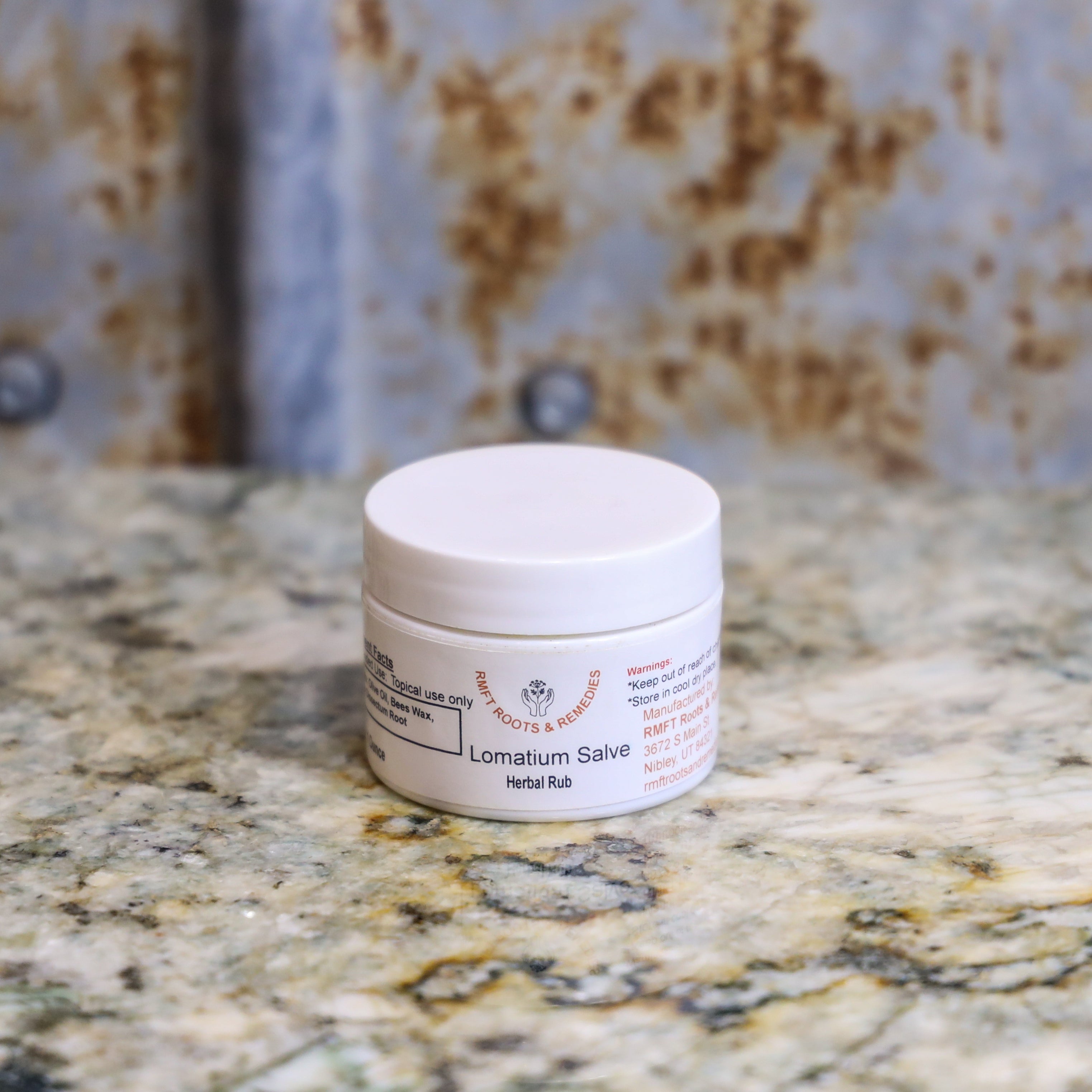 Jar of Lomatium Salve on a marble countertop.