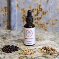 Bottle of 'Mens Formula' herbal supplement on a textured surface with dried herbs.
