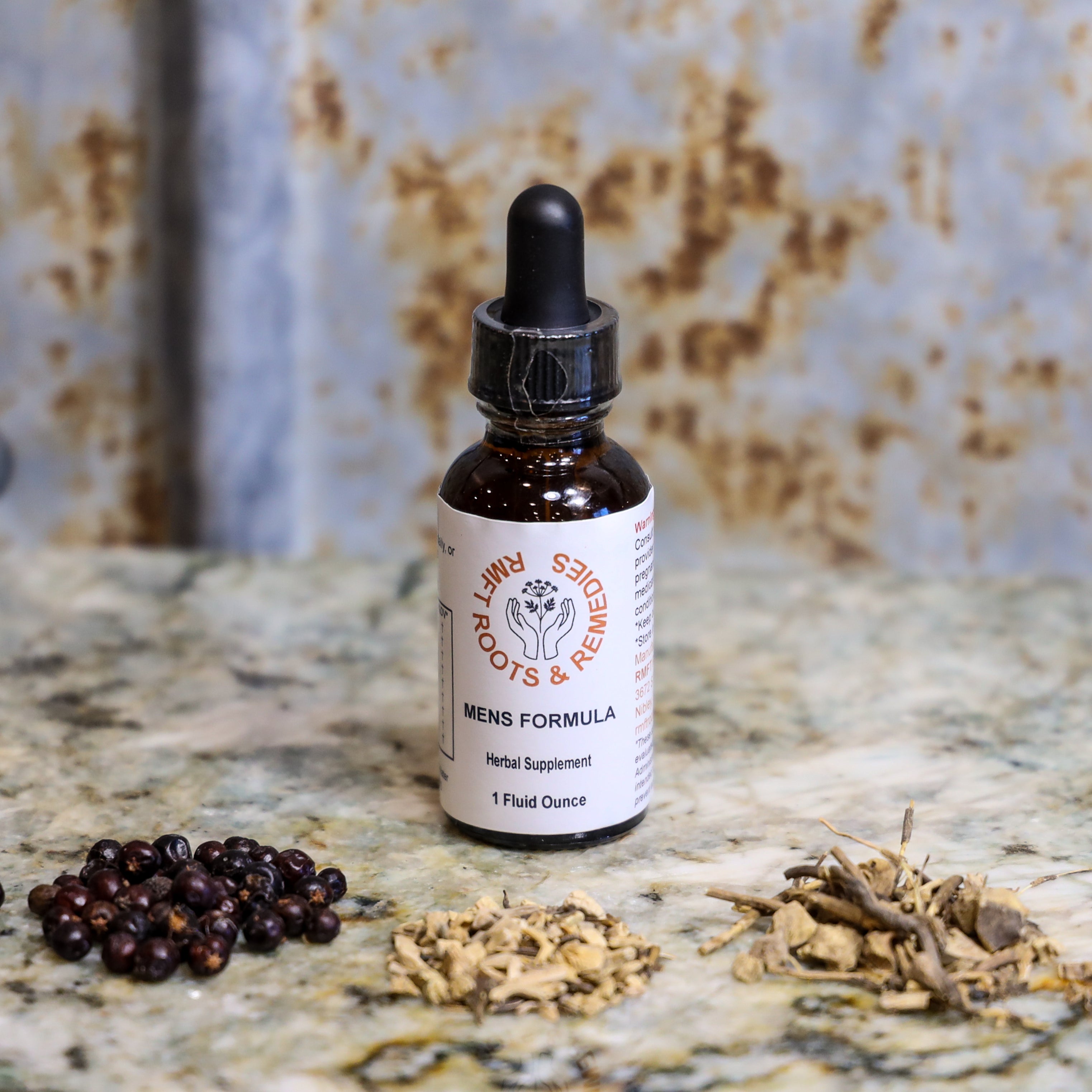 Bottle of 'Mens Formula' herbal supplement on a textured surface with dried herbs.