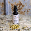 Bottle of 'Oregon Grape' herbal supplement with dried herbs on a marble surface