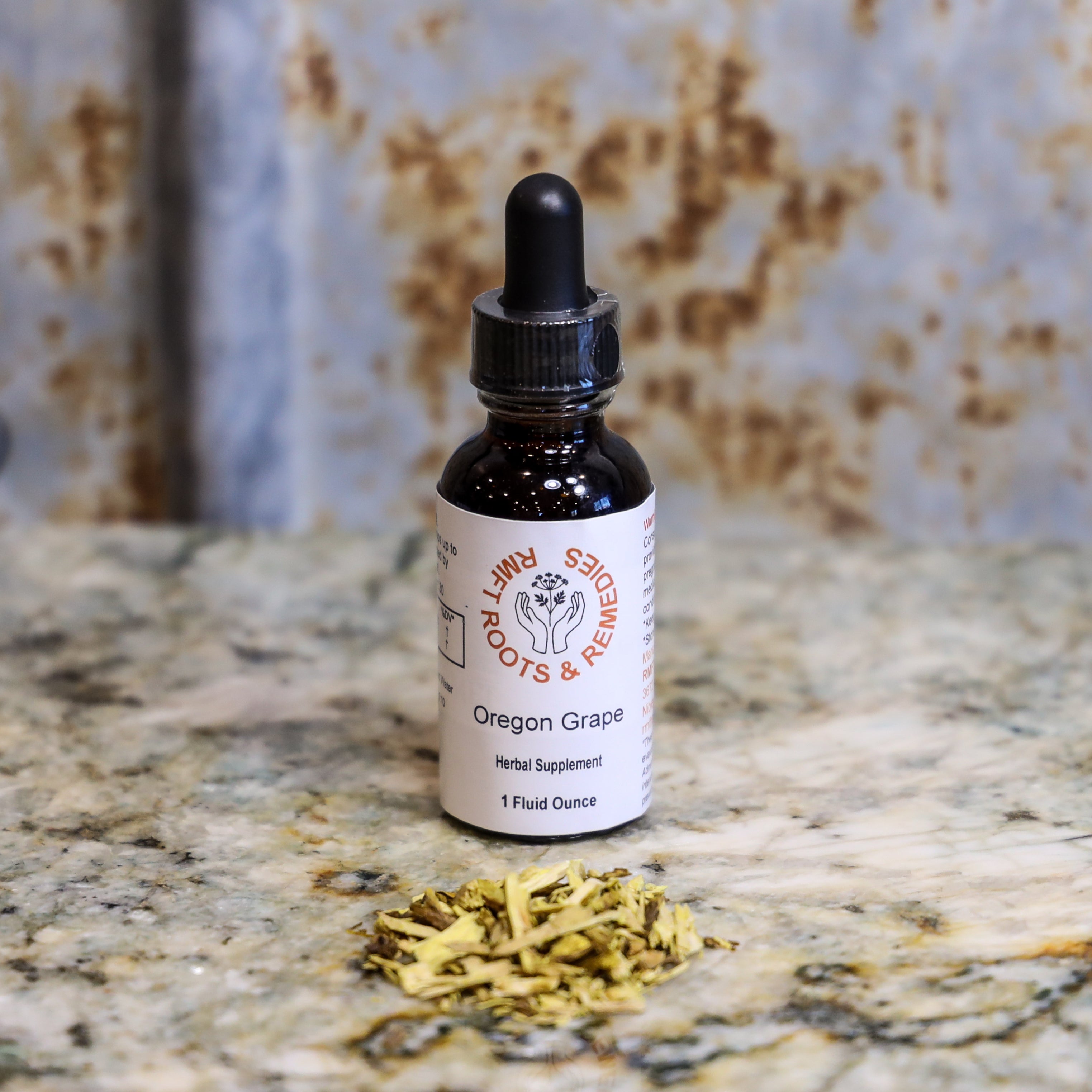 Bottle of 'Oregon Grape' herbal supplement with dried herbs on a marble surface