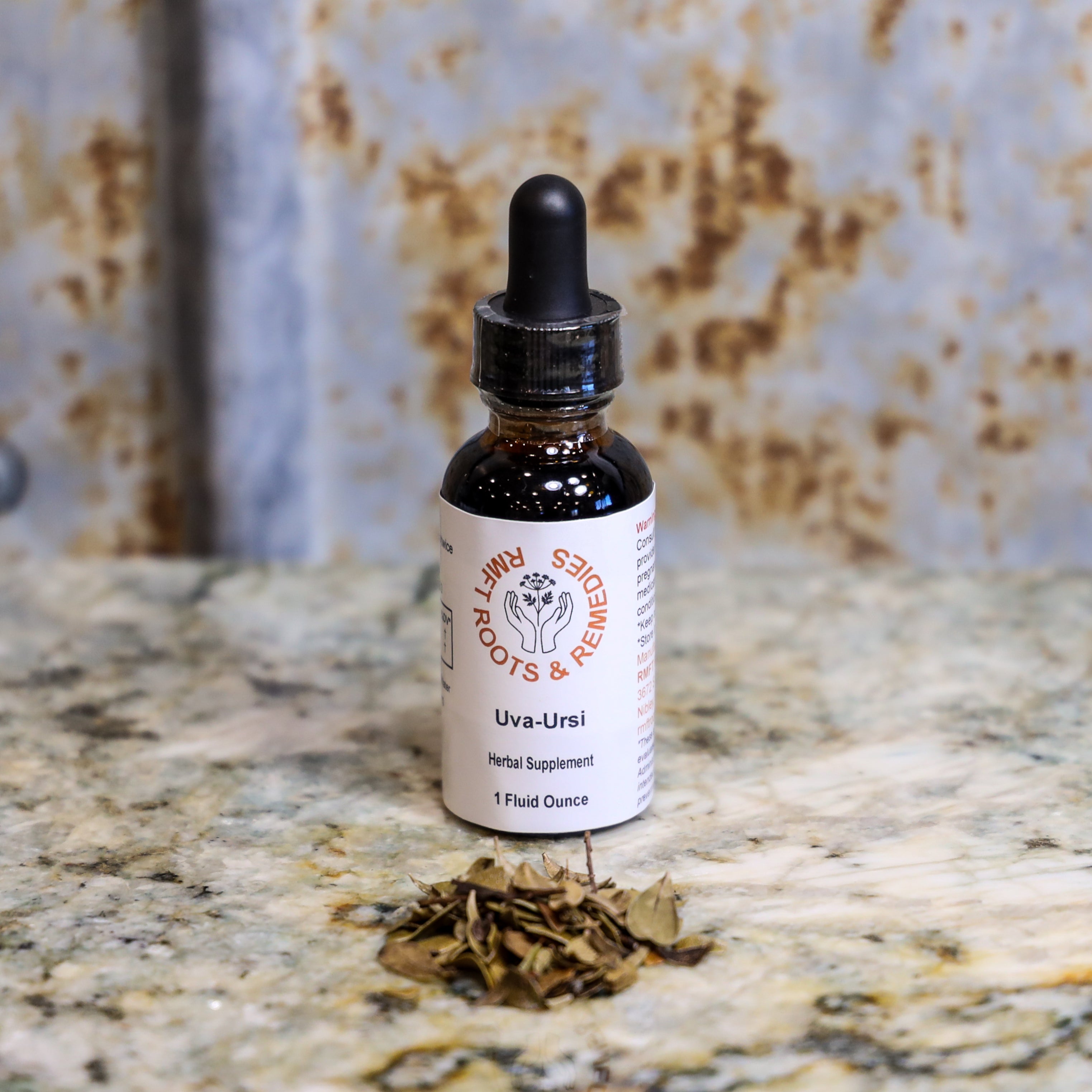 Bottle of Uva-Ursi herbal supplement with dried herbs on a textured surface